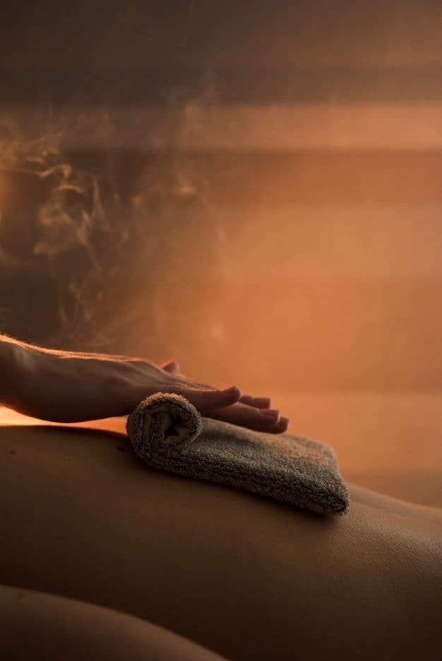Compressa de toalha quente aplicada nas costas durante sessão de massagem terapêutica